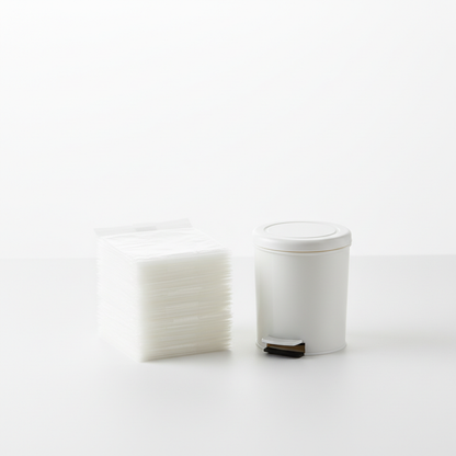 Clear small trash bags folded and stacked next to a small white mini trash can